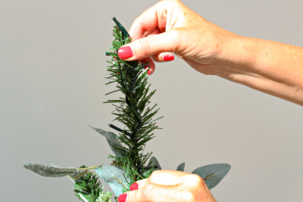 ladies hands wrapping lights around christmas tree